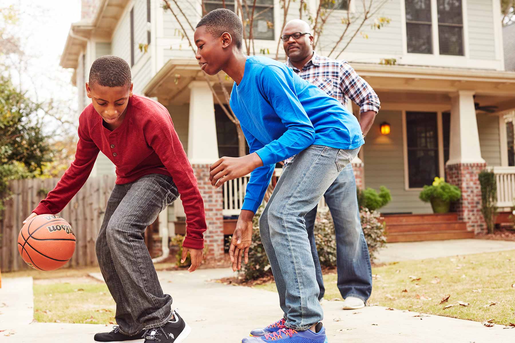 boys playing basketball with dad in the driveway